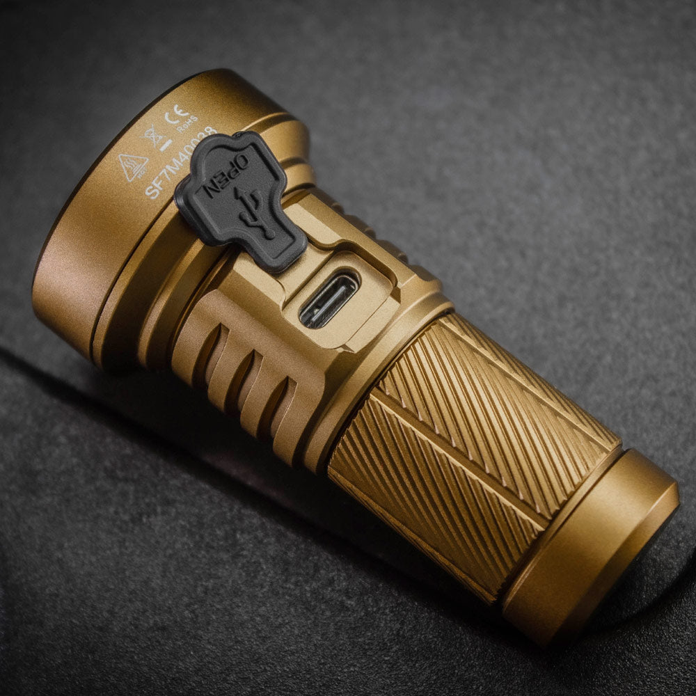 Close-up of the desert tan SPERAS M4 flashlight body showing the protective rubber cover for the USB-C fast charging port