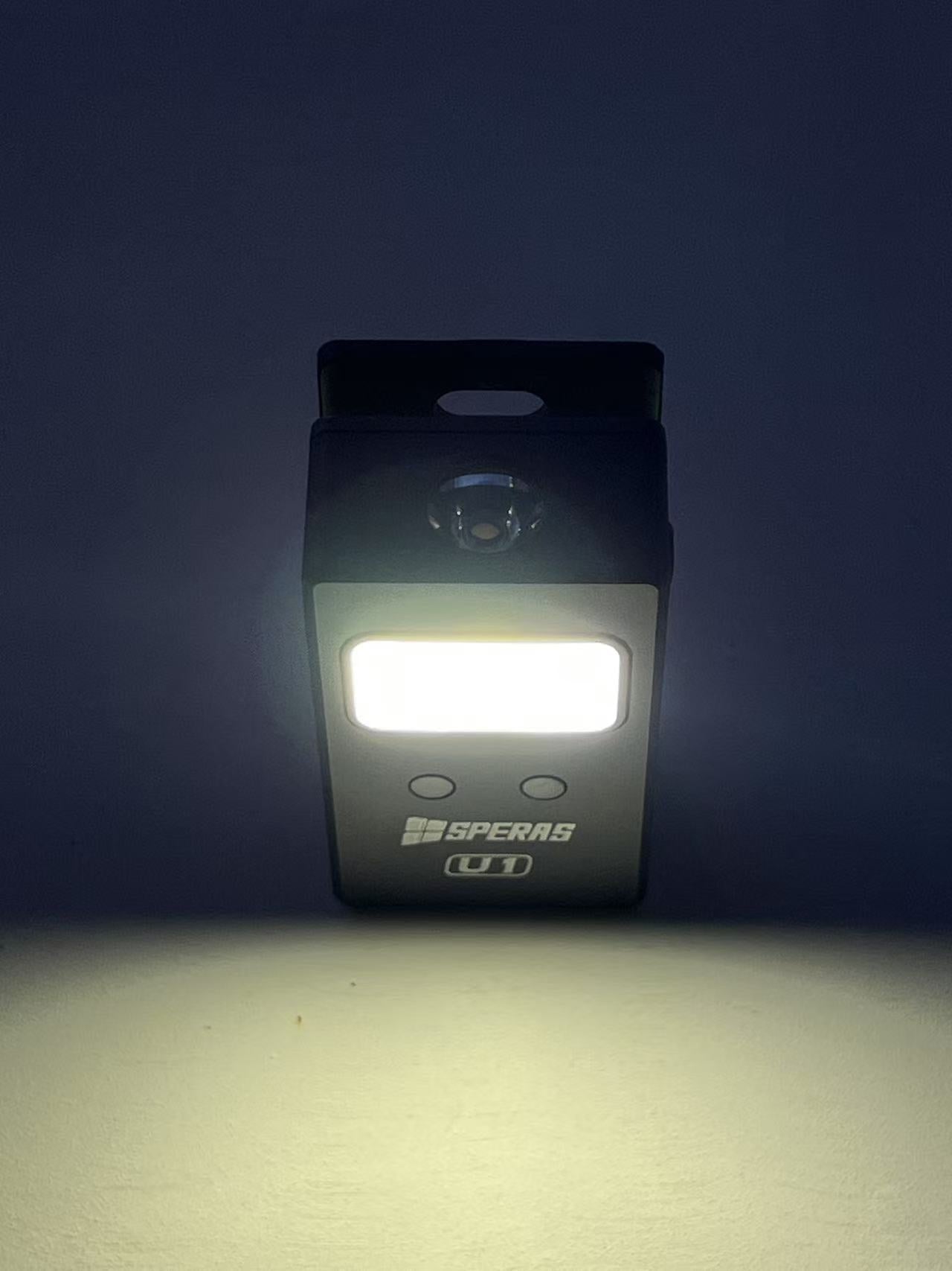 SPERAS U1 clip light illuminating the dark with its wide flood beam, perfect for close-up tasks or serving as a powerful hands-free headlamp.