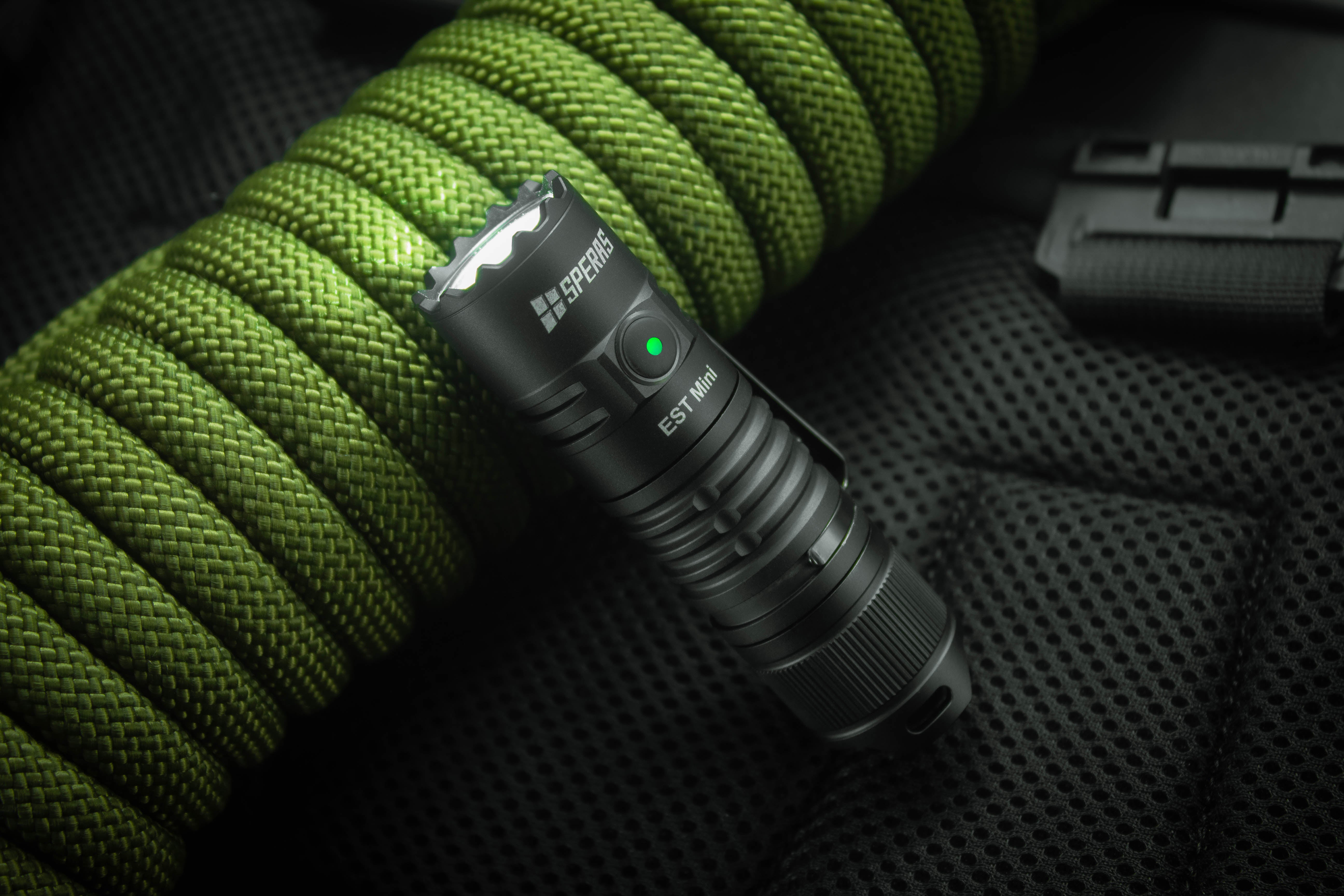 IP68 waterproof SPERAS EST Mini tactical torch machined from aerospace 6061 aluminum alloy resting on green paracord